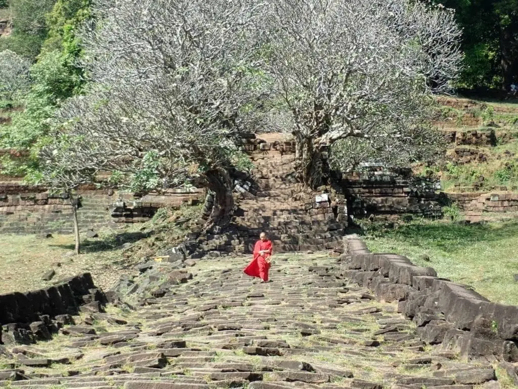 Monk in red robe on ruined walkway of Wat Phu, Laos