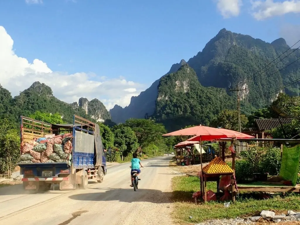 Truck and boy on bicycle on small road in Laos mountains