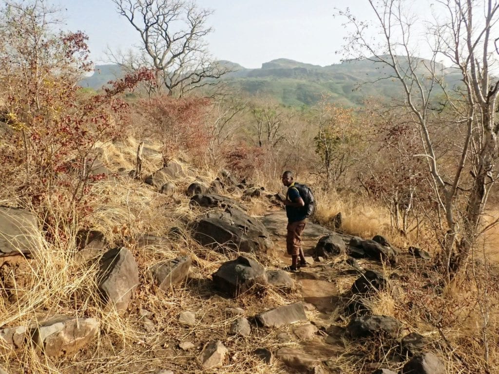 Senegalese trekking guide walks on rocky trail in Guinean highlands