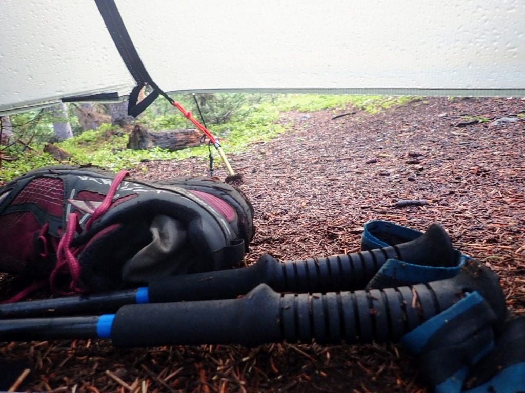 Trail running shoes and hiking poles under tarp