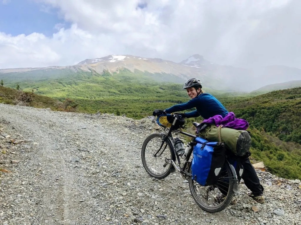 Cyclist pushing touring bike up rough gravel road in Patagonia