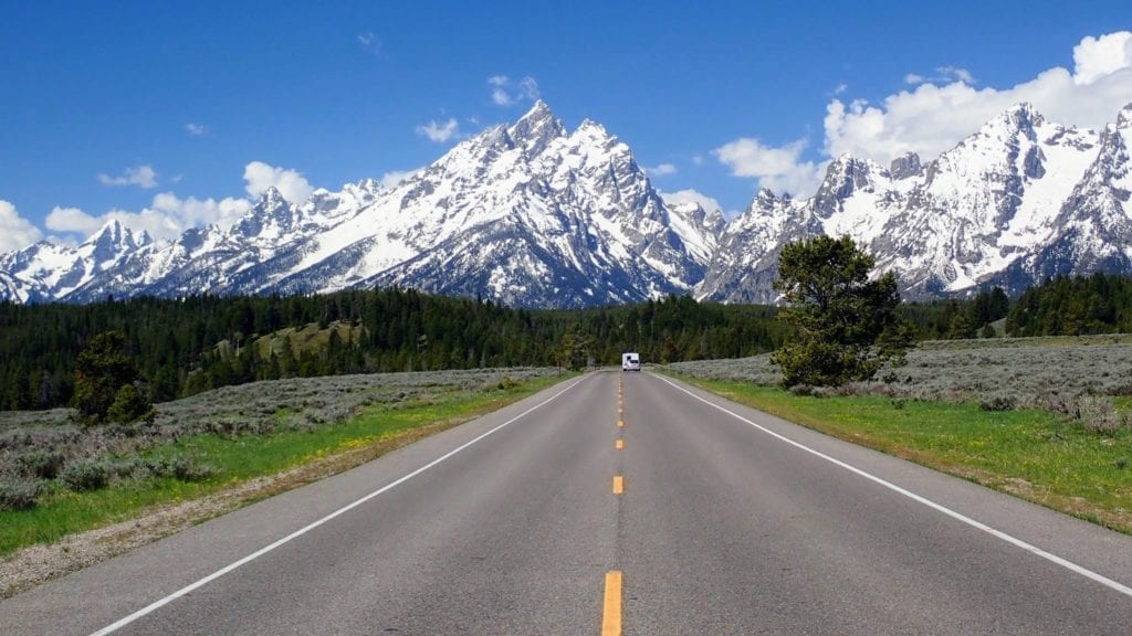 Road heading toward snow-capped mountains in Grand Teton National Park