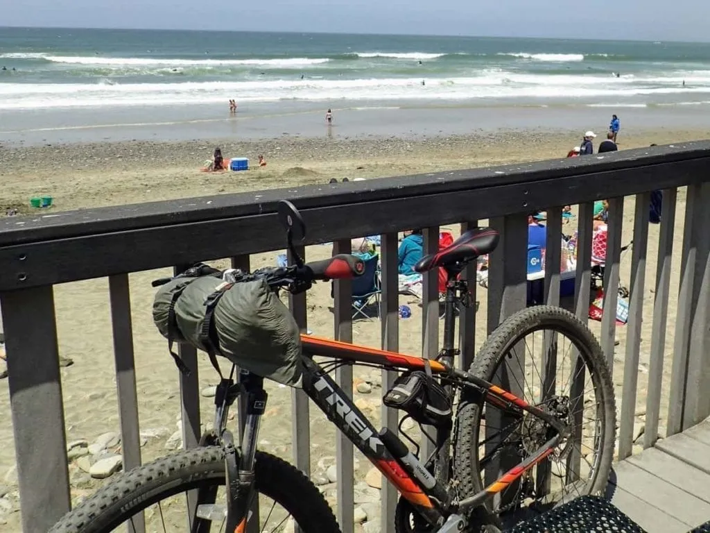 tent strapped to handlebars of mountain bike at beach