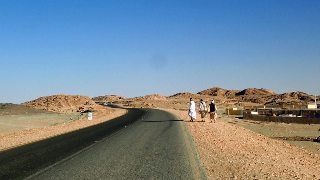 Men walk along a desert highway in northern Sudan