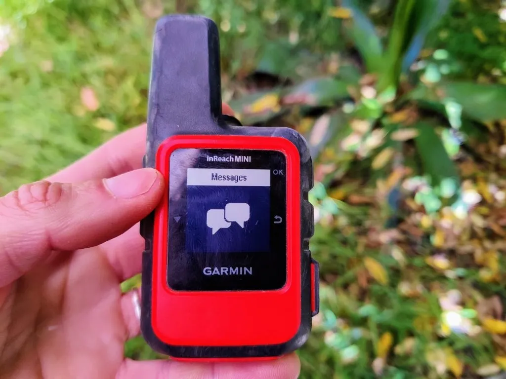 Holding Garmin InReach Mini against backdrop of leaves