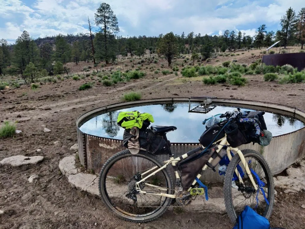 Bikepacking bike leans against cattle tank in high desert