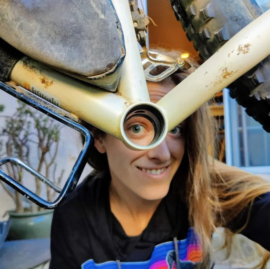 Woman looks through empty bottom bracket shell of bike she is repairing