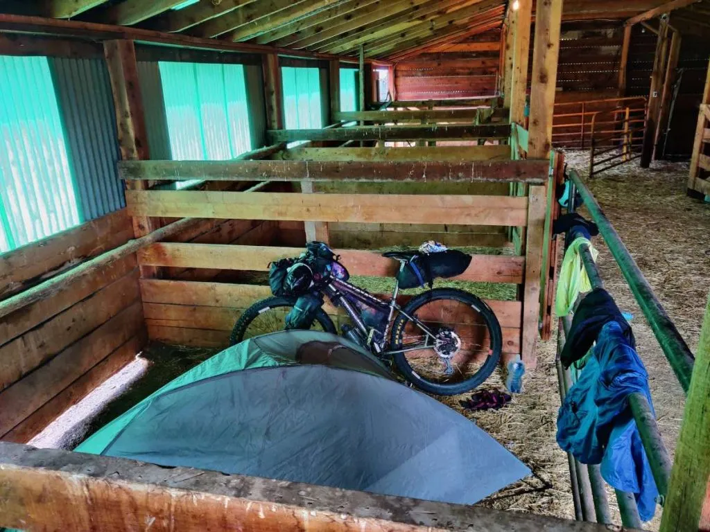 Freestanding bikepacking tent pitched inside barn where tent stakes would be impossible